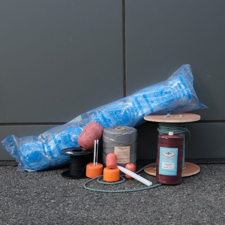 A blue tube of wax sitting on the ground next to candles.